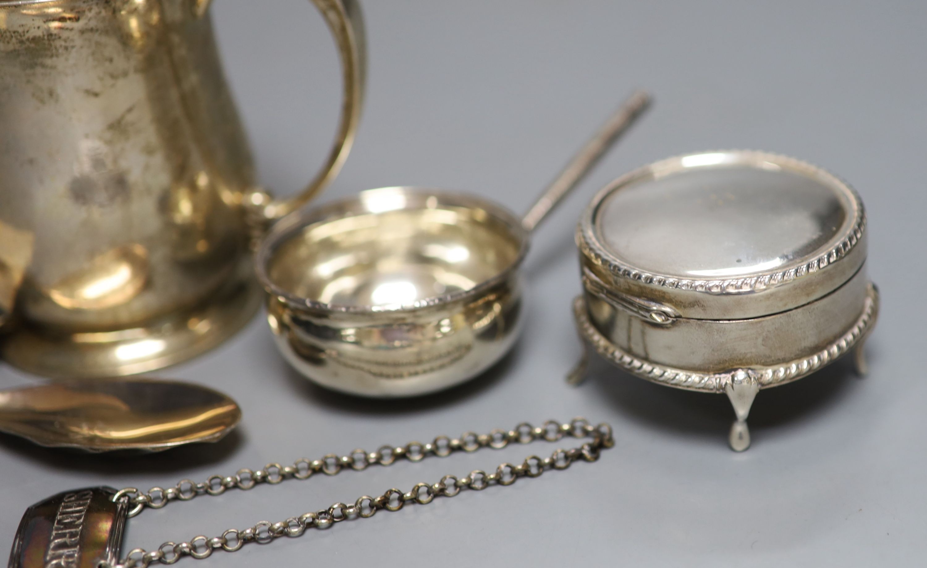 A George V silver mug, a white metal toddy ladle bowl, an Edwardian silver trinket box, a silver reproduction Roman spoon and a George III 'Sherry' label.